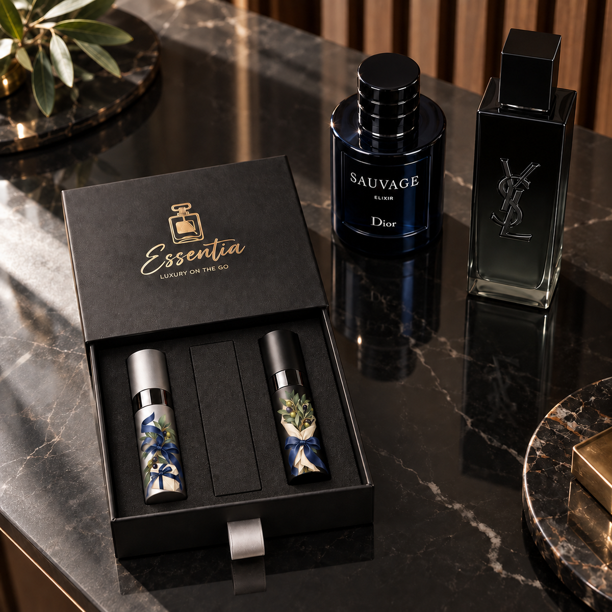 Essentia The First Impression — For Him: 2 decorated 10ml atomizers (silver, black) in a black gift box, with the corresponding full-size fragrance bottles behind.
