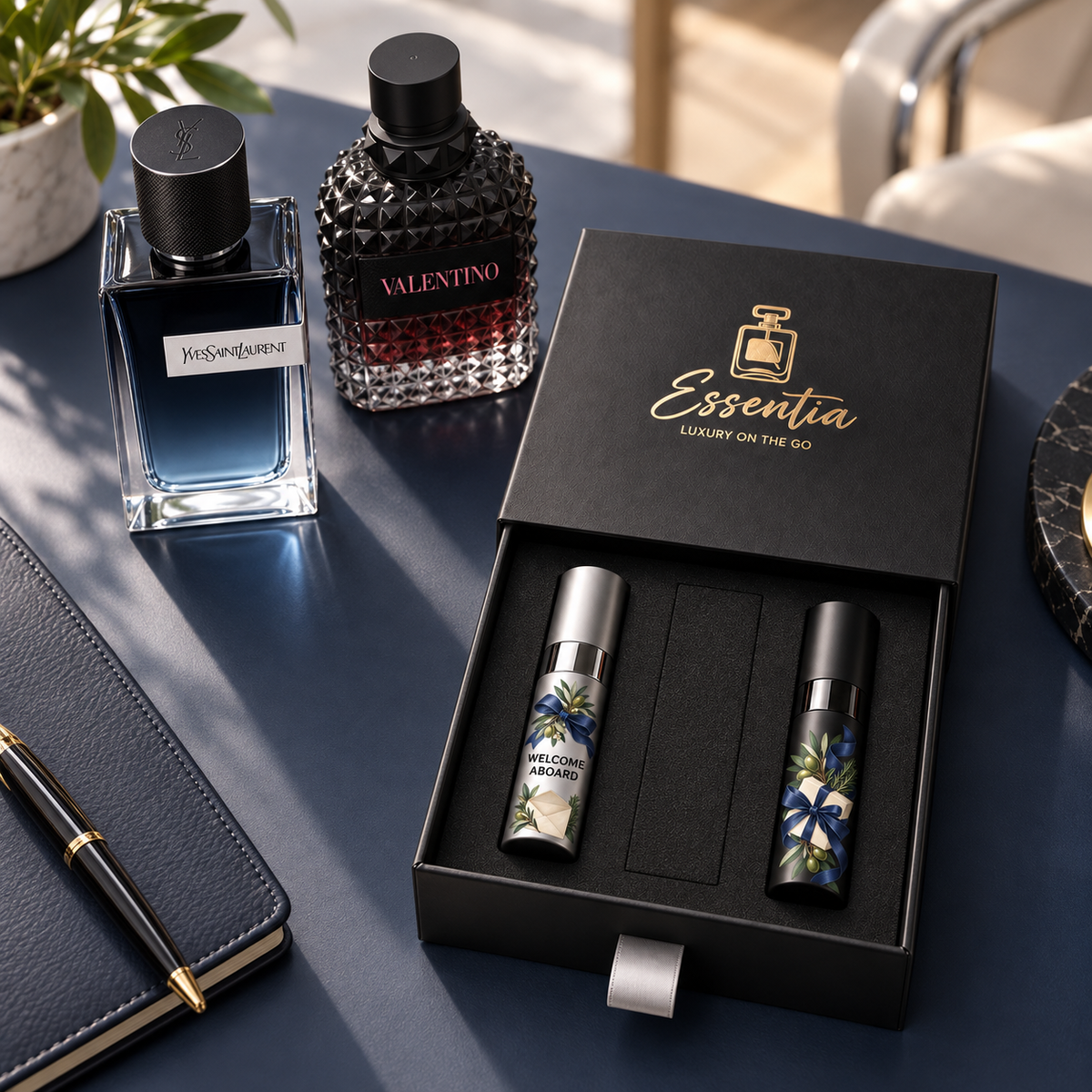 Essentia The Welcome Set — For Him: 2 decorated 10ml atomizers (silver, black) in a black gift box, with the corresponding full-size fragrance bottles behind.