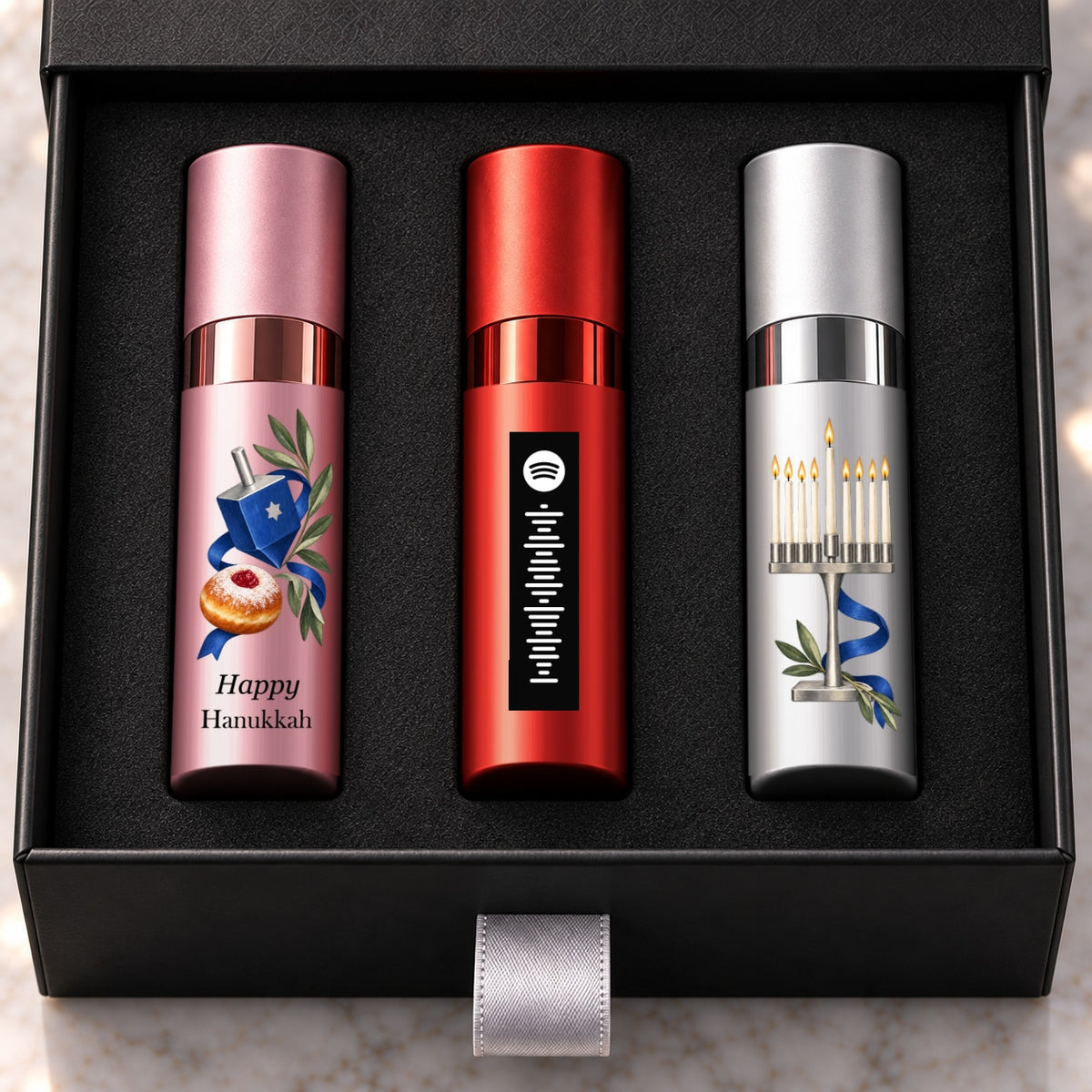 Hanukkah Fragrance Gift Set for Her — artwork detail. Original black Happy Hanukkah lettering on the pink atomizer and aligned shared motif.