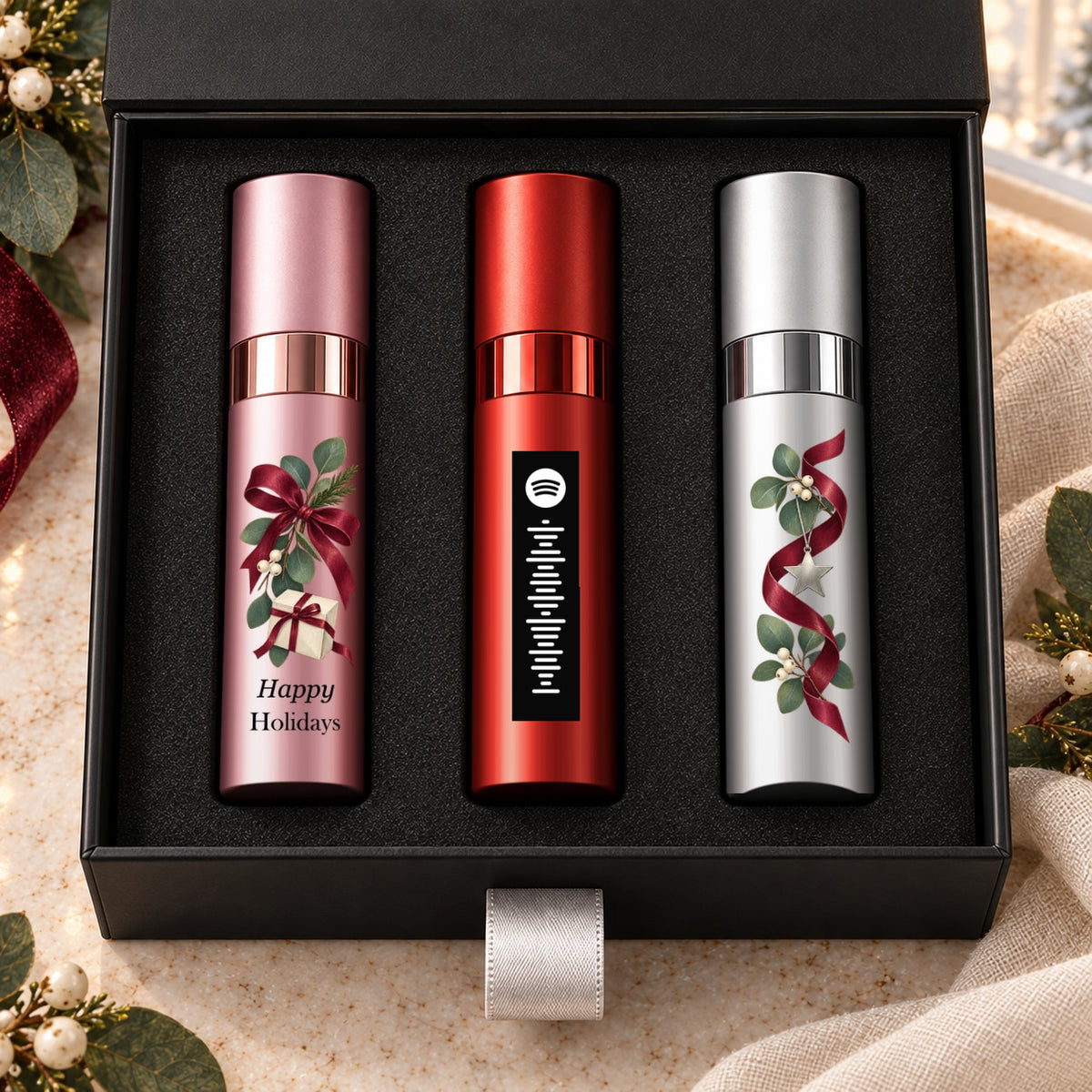 Happy Holidays Fragrance Gift Set for Her — artwork detail. Pink, red and silver atomizers with festive artwork in the Essentia gift box.