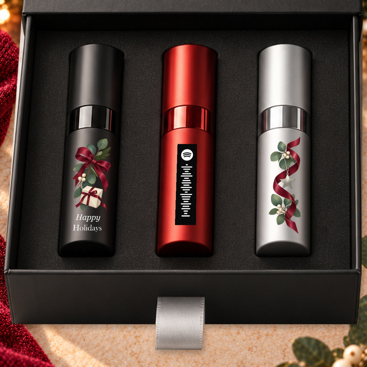 Happy Holidays Fragrance Gift Set for Him — artwork detail. Black, red and silver atomizers with festive artwork in the Essentia gift box.